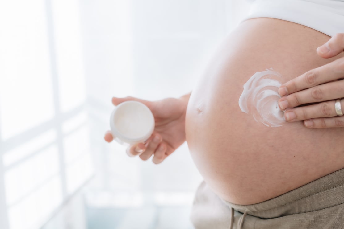 pregnant woman's hand applying moisturizing cream on the skin of her belly to prevent pregnancy stretch marks. concept health care in pregnancy and skin care